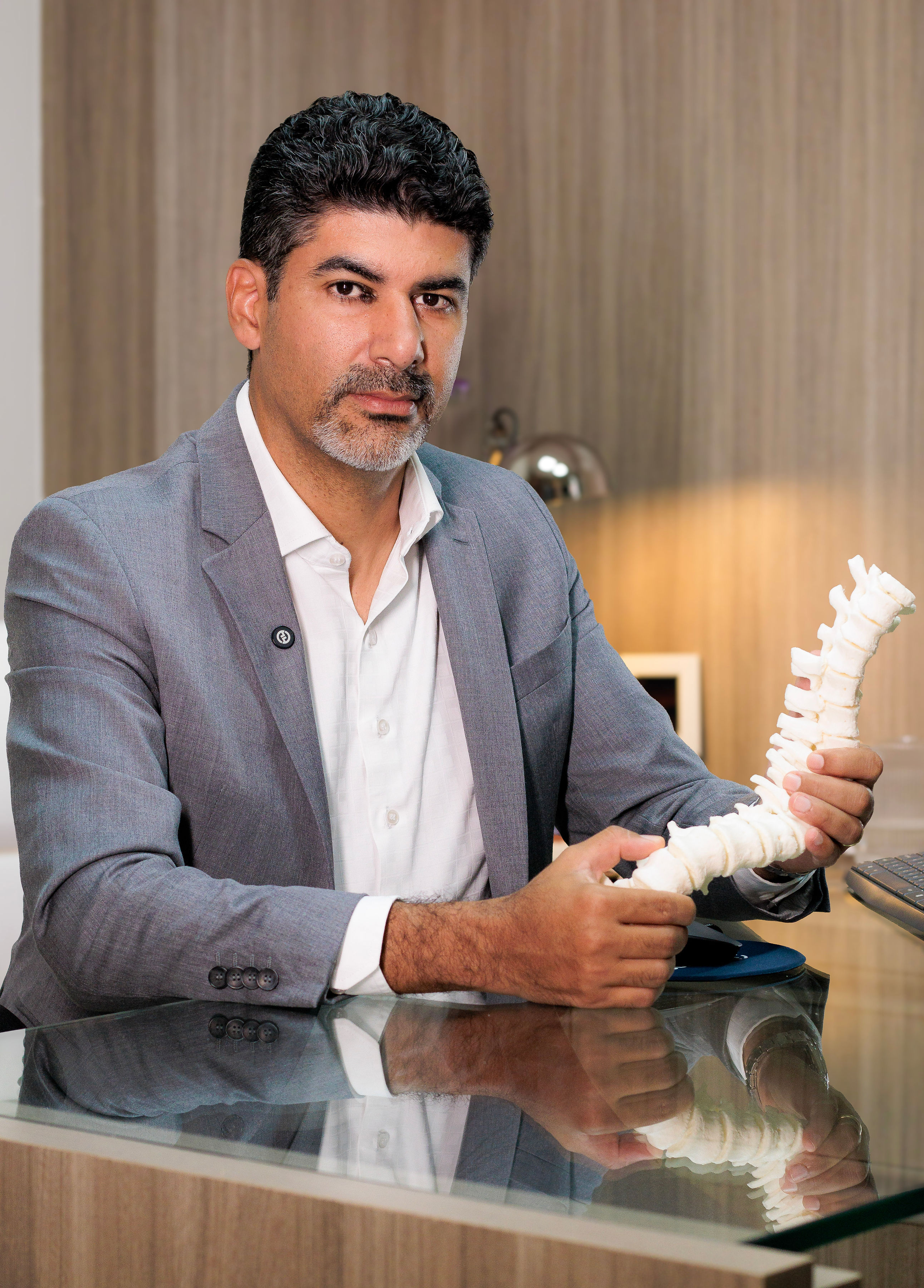 Dr. Chrystiano Cardoso, neurocirurgião, segurando um modelo anatômico de coluna vertebral